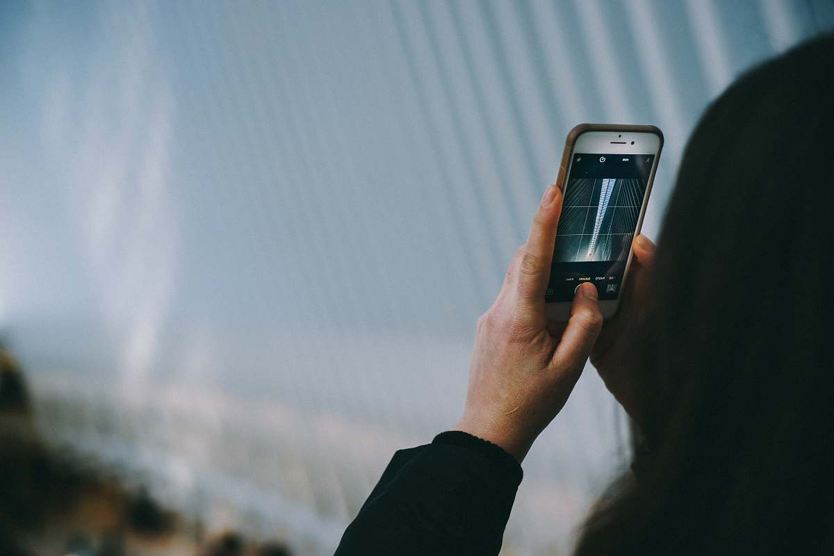 In this captivating scene, a focused woman utilizes her modern camera to photograph the stunning architecture of a bridge, showcasing the harmony between technology and urban design. This image perfectly encapsulates the essence of city life, making it ideal for marketing materials, travel blogs, or lifestyle magazines that highlight innovation and the beauty of urban landscapes.